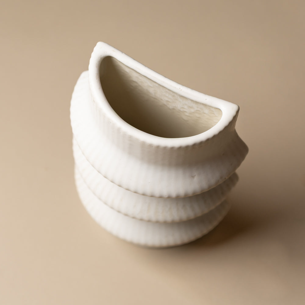 claude-bookend-vase-ripple White ceramic vase with textured design on a beige background