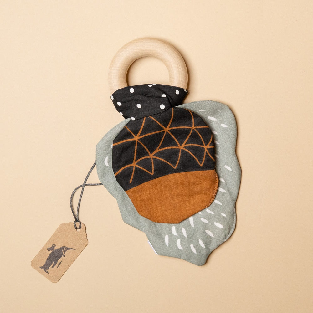 crinkle-teether-acorn Fabric teething ring with wooden handle on a beige background