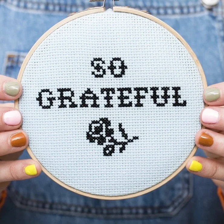 cross-stitch-kit-so-gratefuEmbroidery hoop with 'So Grateful' cross-stitch design held by a person wearing denim. 