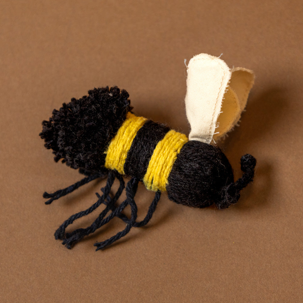 daisy-floor-cushion-pink Pom-pom bee toy on a brown background
