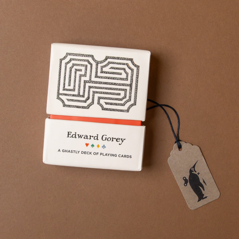 Playing card set by Edward Gorey with a tag on a brown background