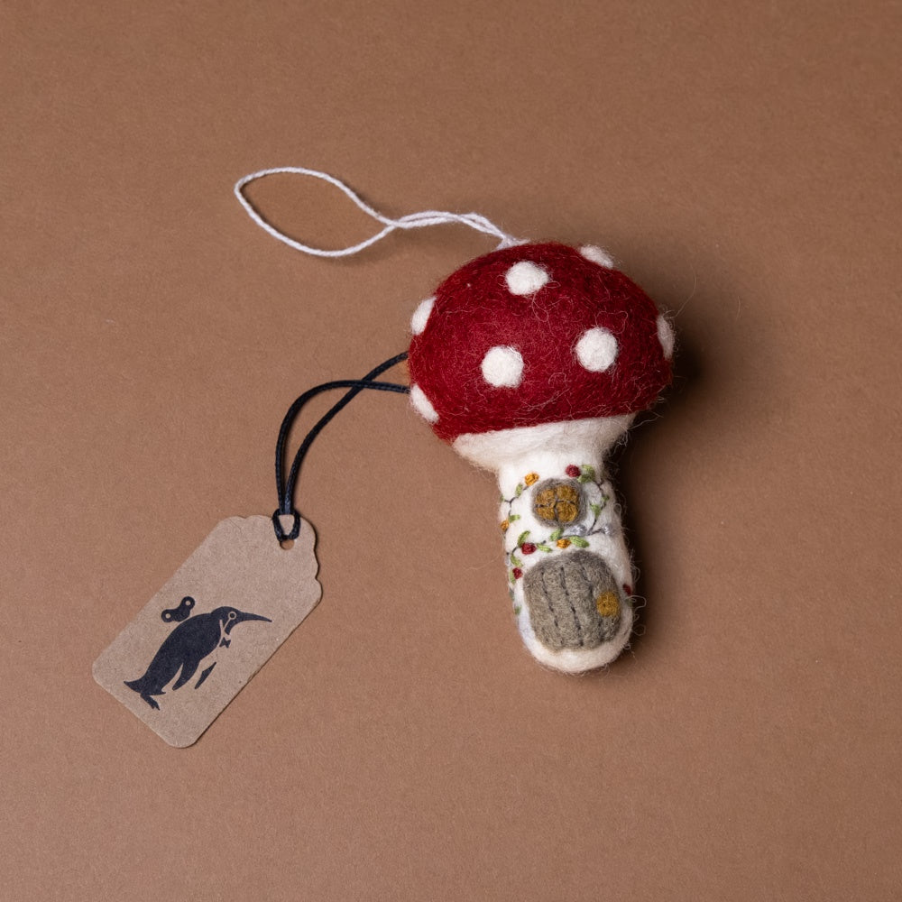 felt-embroidered-mushroom-house-ornament Felted mushroom ornament with red cap and white spots on a brown background