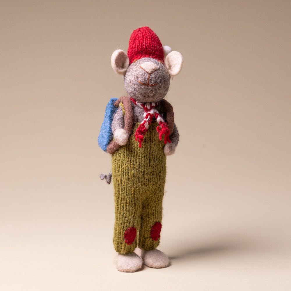 felted-grey-mouse-green-overalls-and-back-pack Toy mouse with a red hat, backpack, and green pants on a beige background
