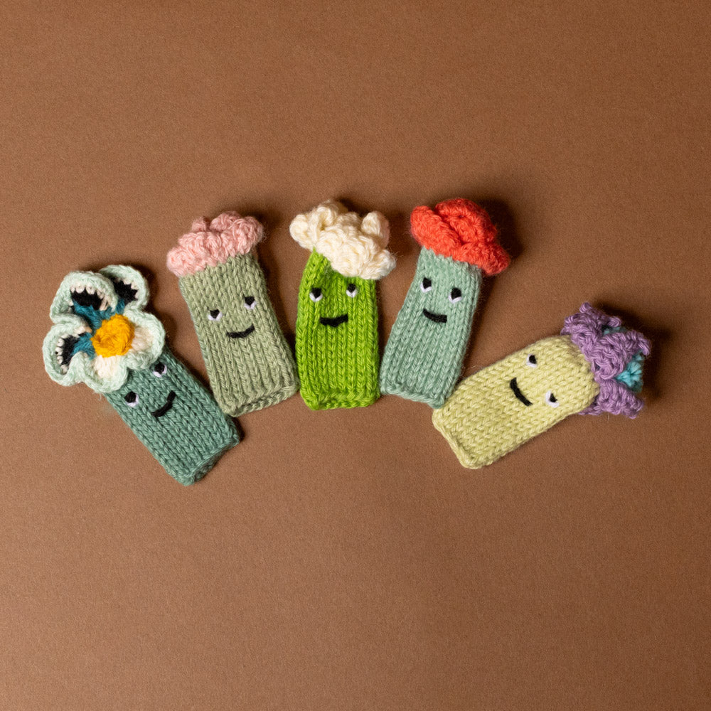 Five  hand-knit-finger-puppet-set-flowers with faces on a brown background