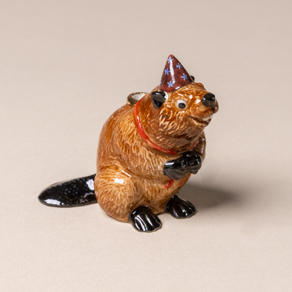 heirloom-porcelain-cake-topper-Beaver figurine wearing a party hat on a beige background