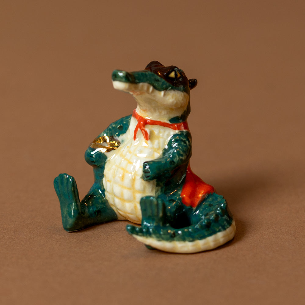 heirloom-porcelain-cake-topper-super-gator with a red scarf on a brown background