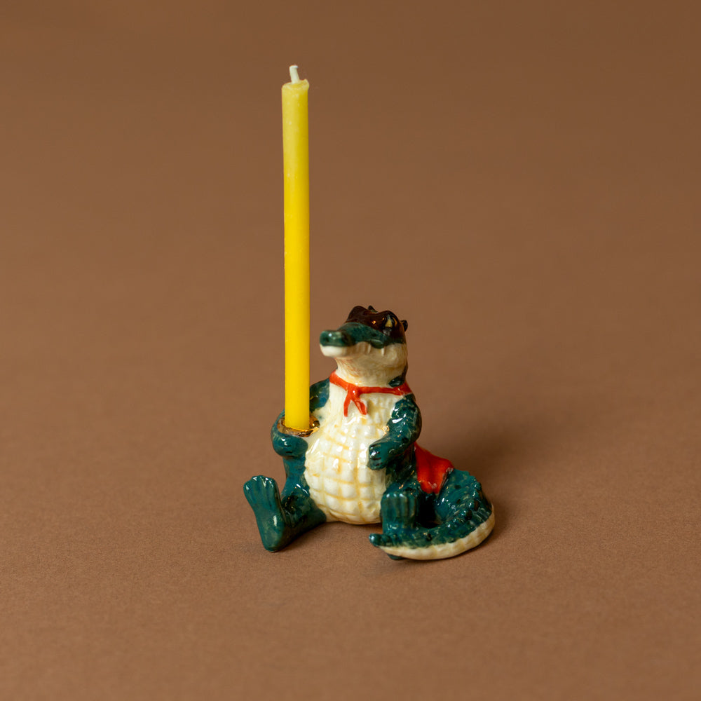 heirloom-porcelain-cake-topper-super-gator with a yellow candle on a brown background