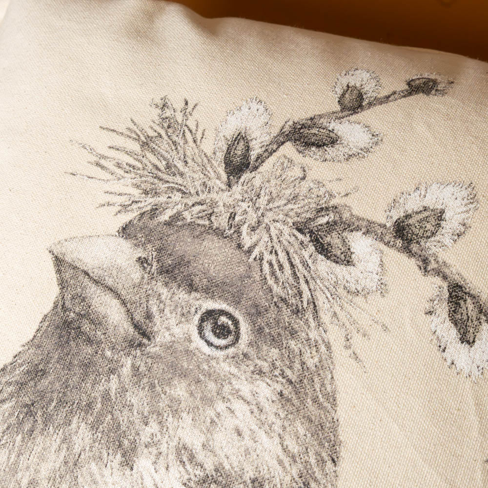 howard-the-house-finch-pillow Close-up of a decorative pillow with a bird and branch design on a beige background