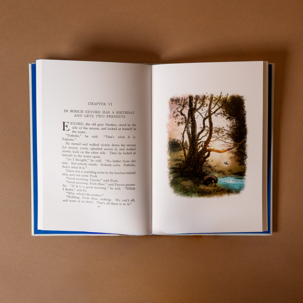 leather-bound-winnie-the-pooh-classic-edition Open book with text and a scenic illustration on a brown background