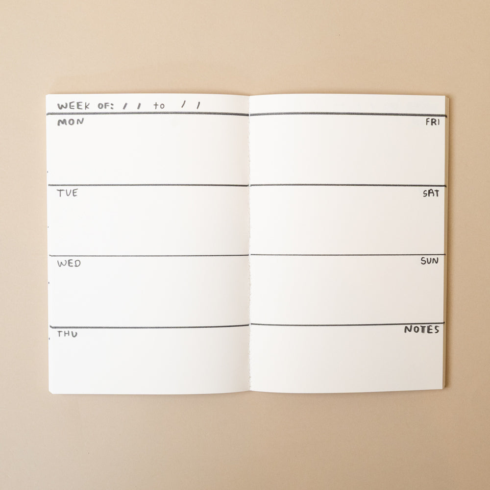 Open life-is-happening-planning-journal with weekly schedule on a beige background