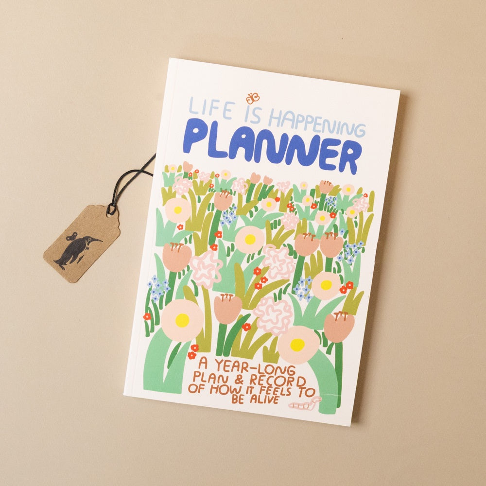 Planner with floral design and 'Life is Happening' text on a beige background