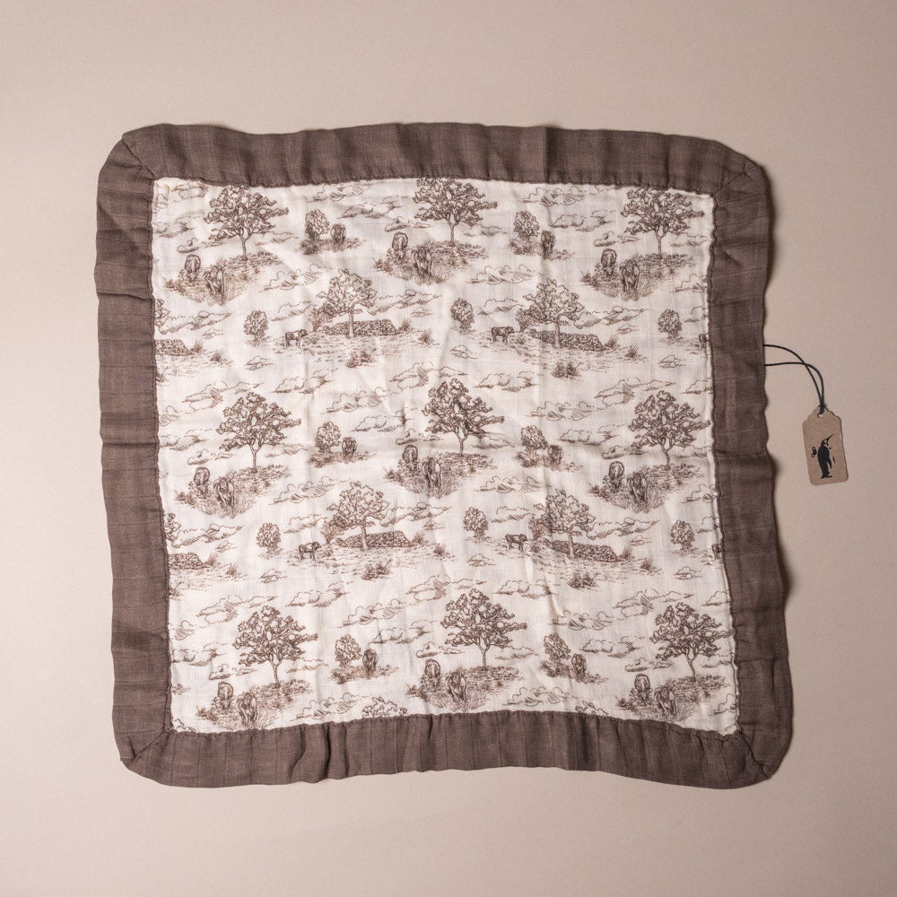 little-lovie-meadow-toile Fabric square with nature-themed pattern and brown border on a beige background