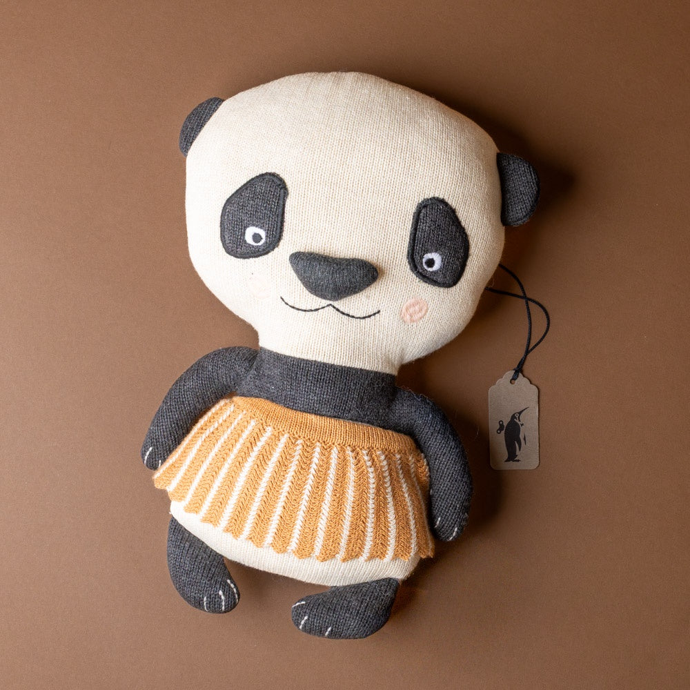 lun-lun-panda-bear Stuffed panda toy with a yellow skirt on a brown background