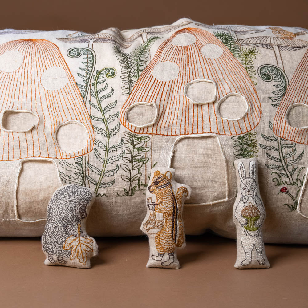 mushroom-forest-pocket-pillow Embroidered mushroom design on a fabric background with small embroidered animals.