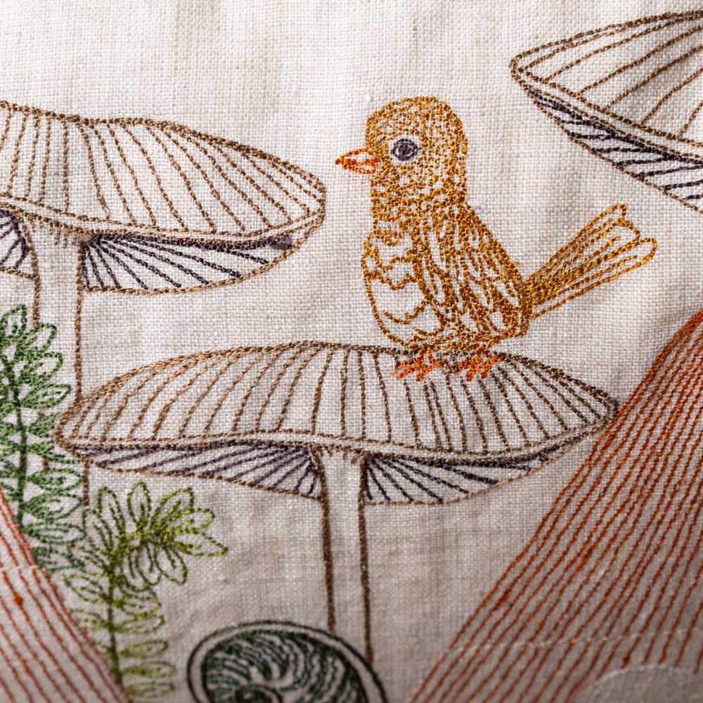 mushroom-forest-pocket-pillow Embroidered design of a bird on a mushroom with a natural background