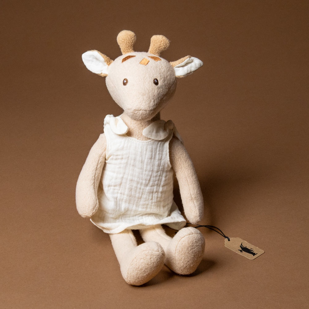 organic-cotton-leonie-giraffe--grande Stuffed  toy with a tag on a brown background