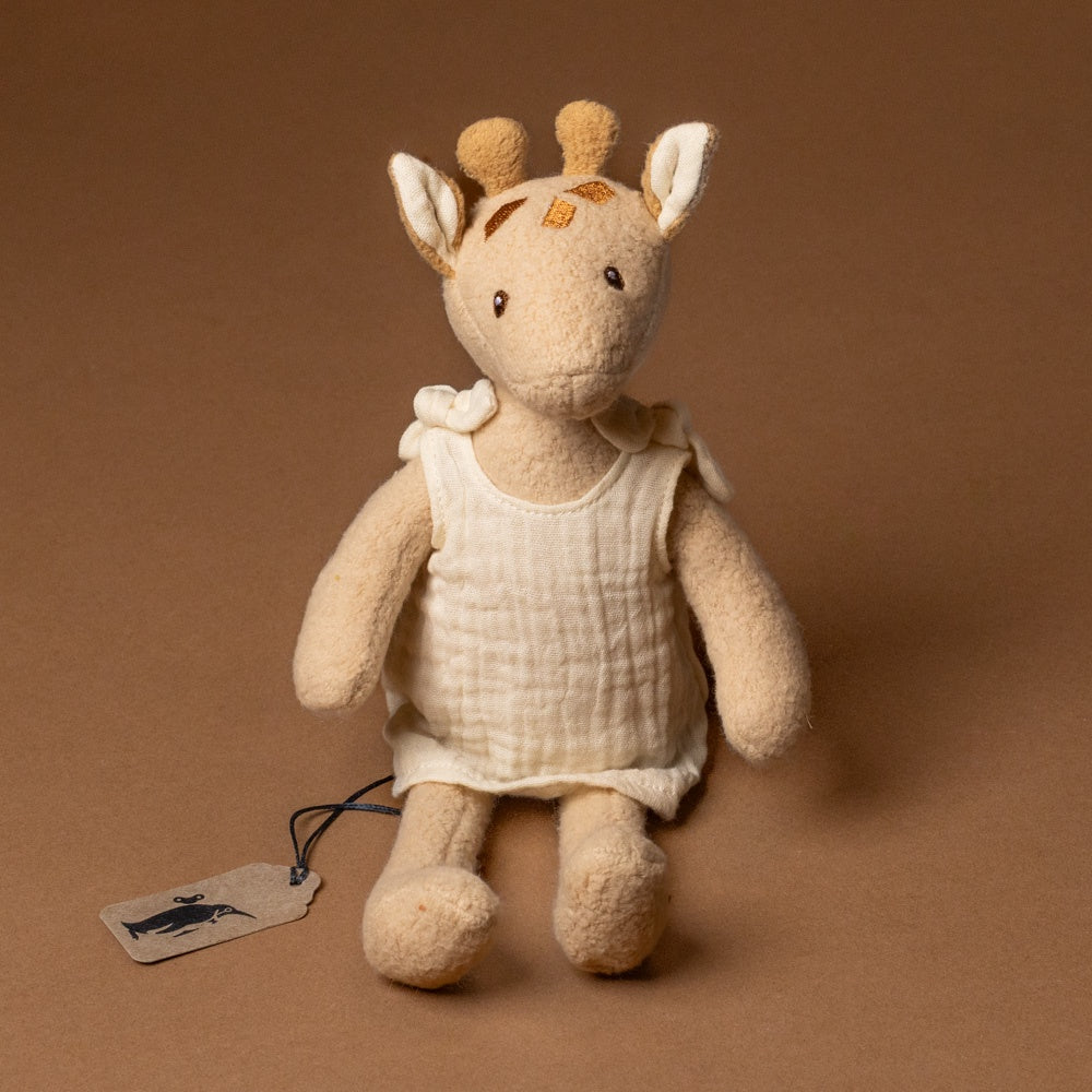 organic-cotton-leonie-giraffe--petite Stuffed toy with a white dress on a brown background