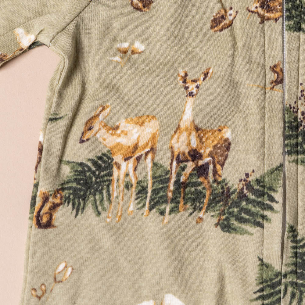 organic-cotton-zipper-pajamas-forest-party Close-up of a green fabric with deer and nature-themed print
