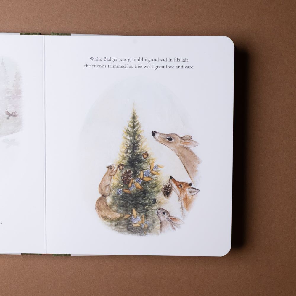 our-little-adventure-at-christmas-board-book Illustrated book page with animals around a Christmas tree on a brown background
