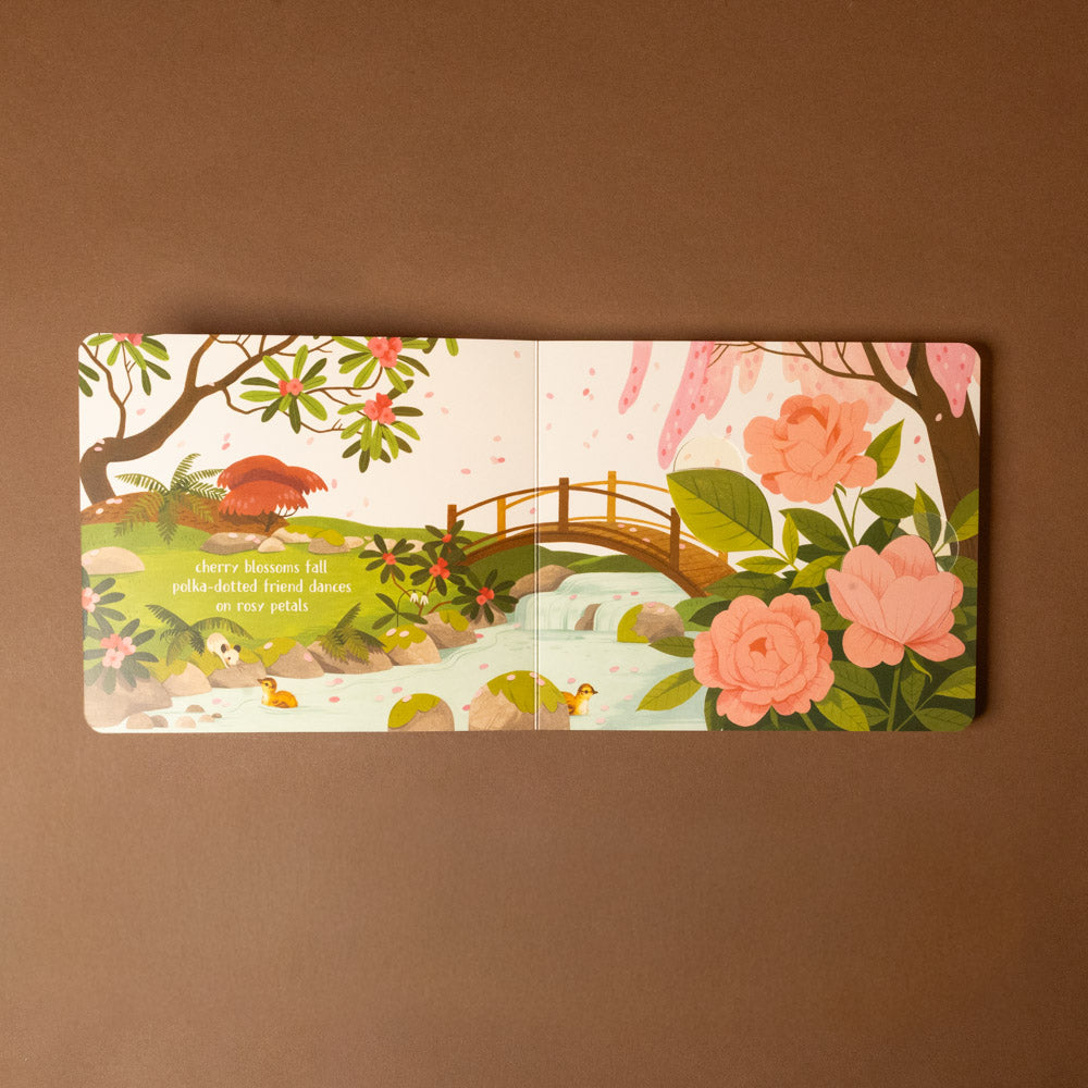 peek-a-boo-haiku-board-book Illustrated book open to a page with a bridge and flowers on a brown background