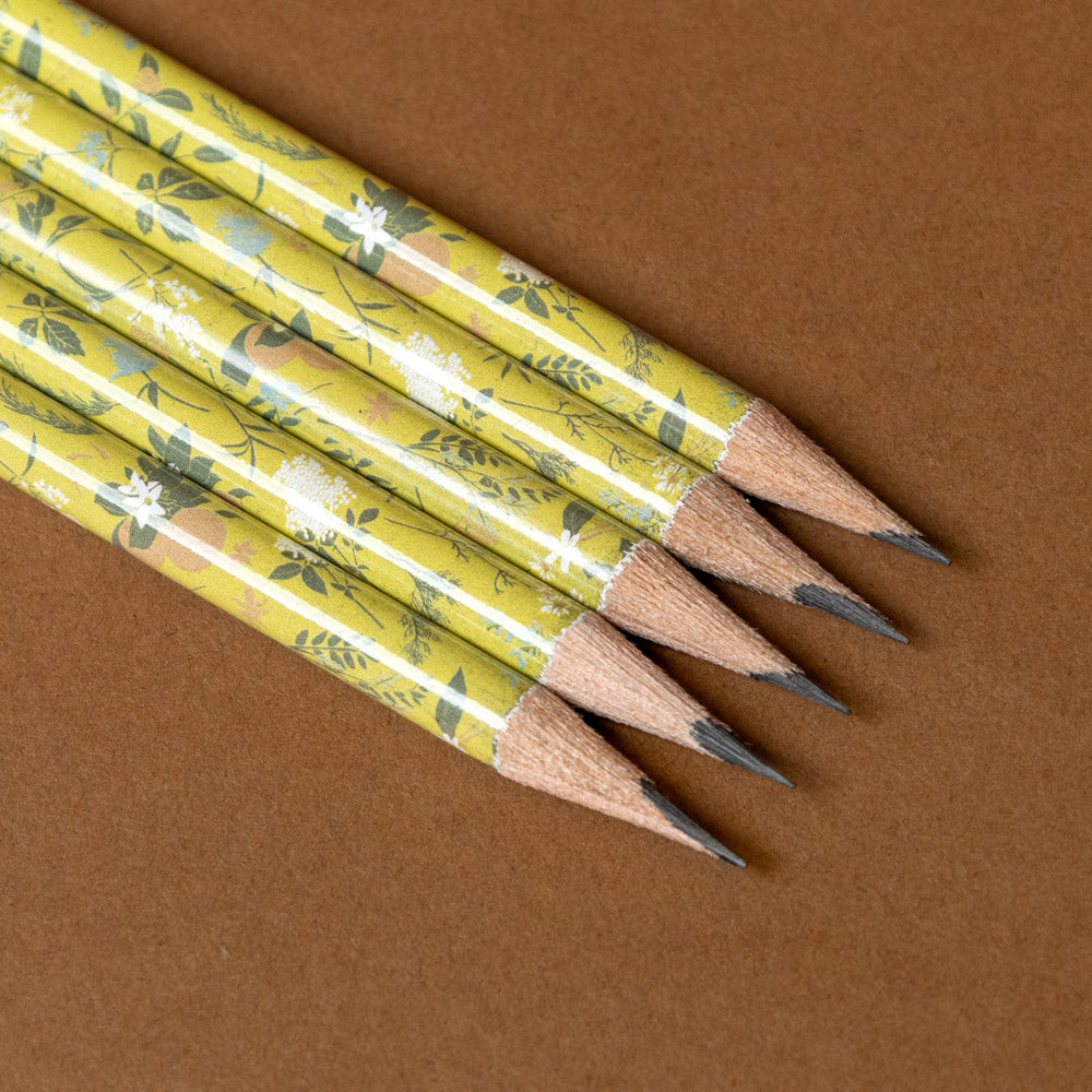 Set of pencils with decorative yellow wraps on a brown background