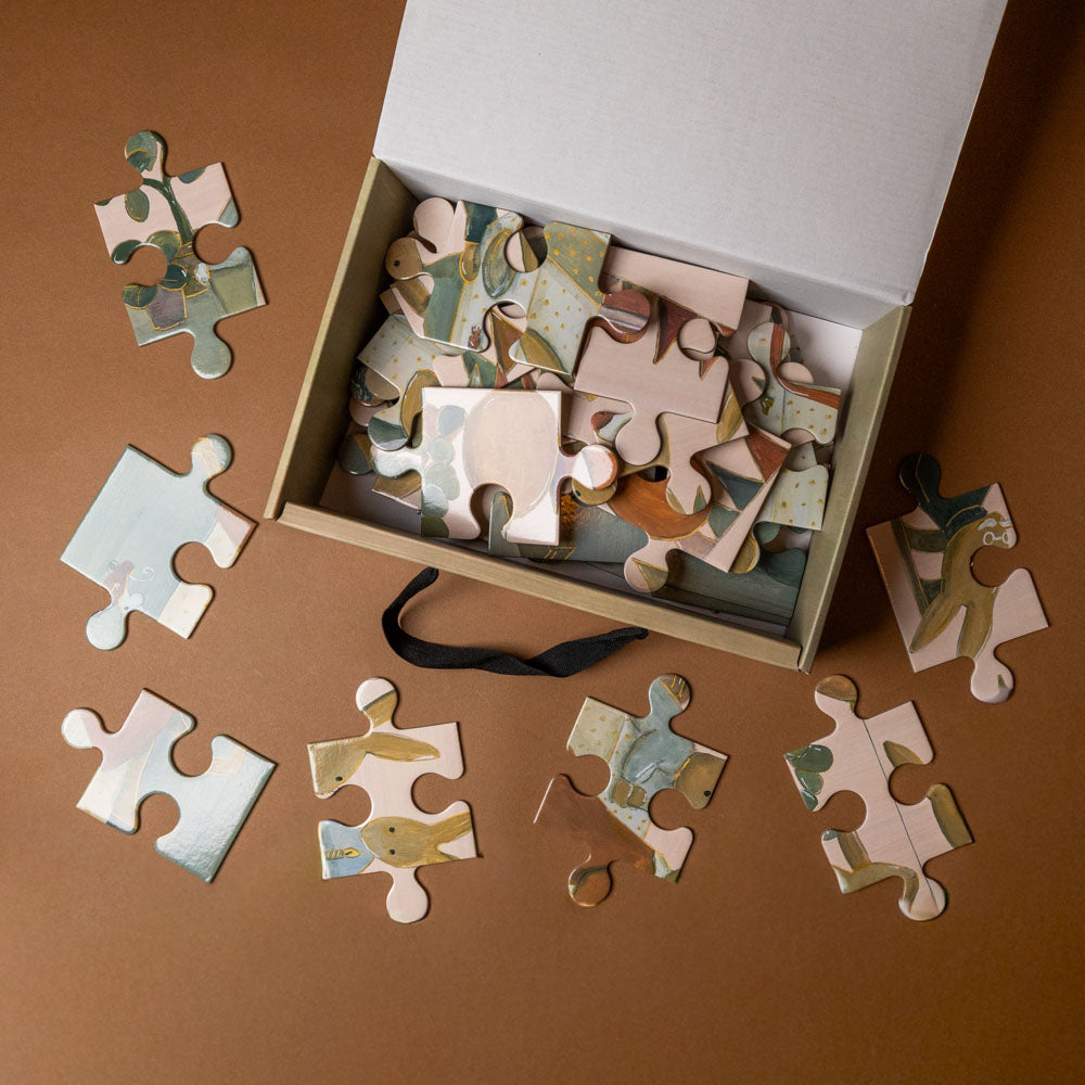 rabbit-family-40-piece-floor-puzzle Jigsaw puzzle pieces on a brown surface with a box of puzzle pieces.