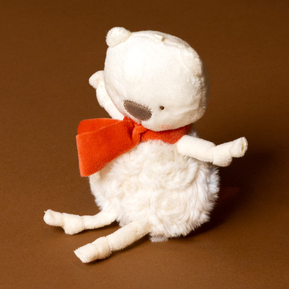 White plush roly-poly-polar-bear- ith a red bow tie on a brown background
