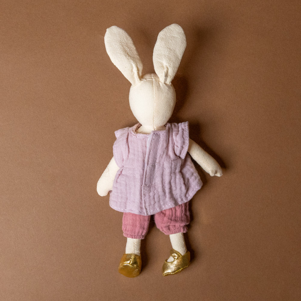 sidonie-the-rabbit-petite Stuffed bunny toy wearing a pink outfit on a brown background