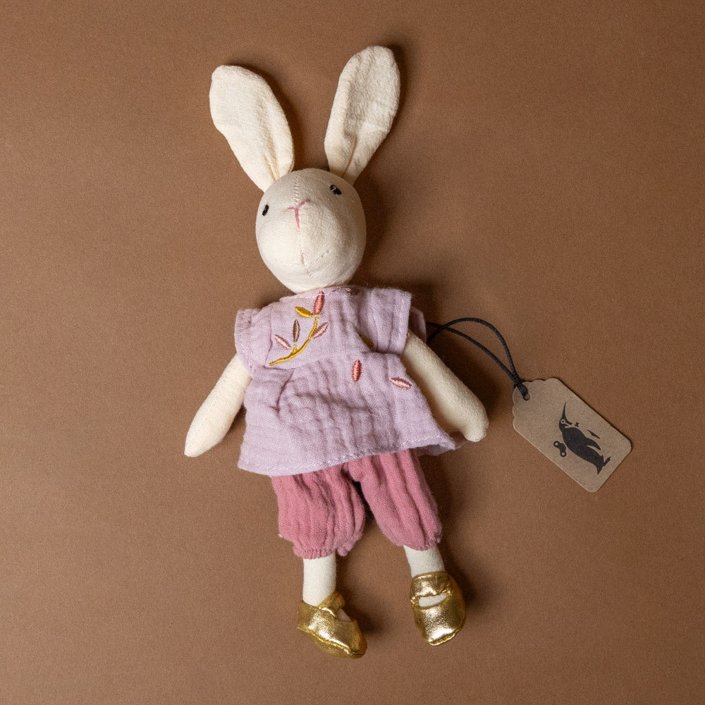 sidonie-the-rabbit-petite Stuffed rabbit toy with a pink outfit on a brown background