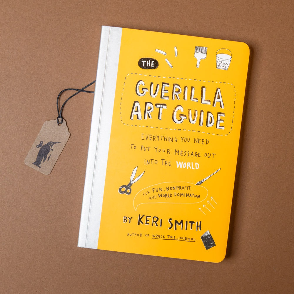 Yellow book titled 'The Guerilla Art Guide' by Keri Smith on a brown background