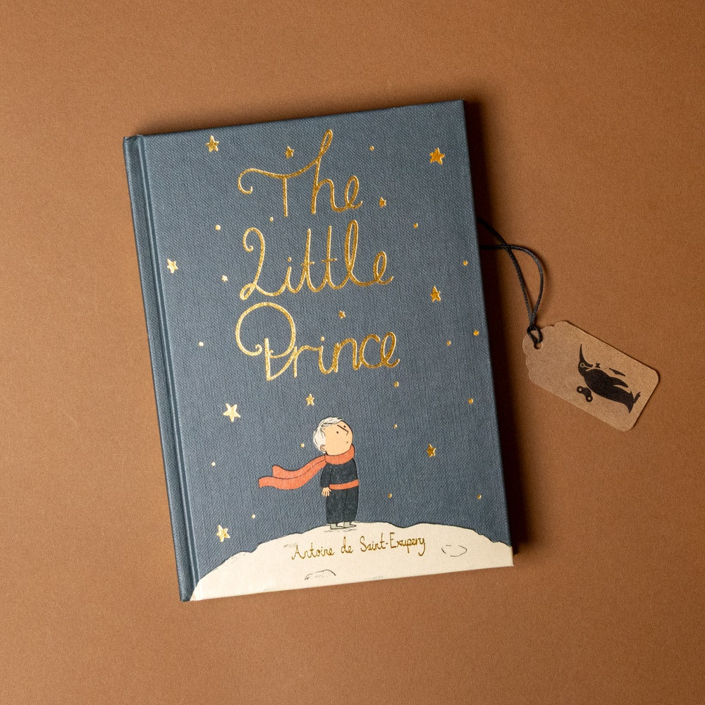 Book titled 'The Little Prince' with a tag on a brown background