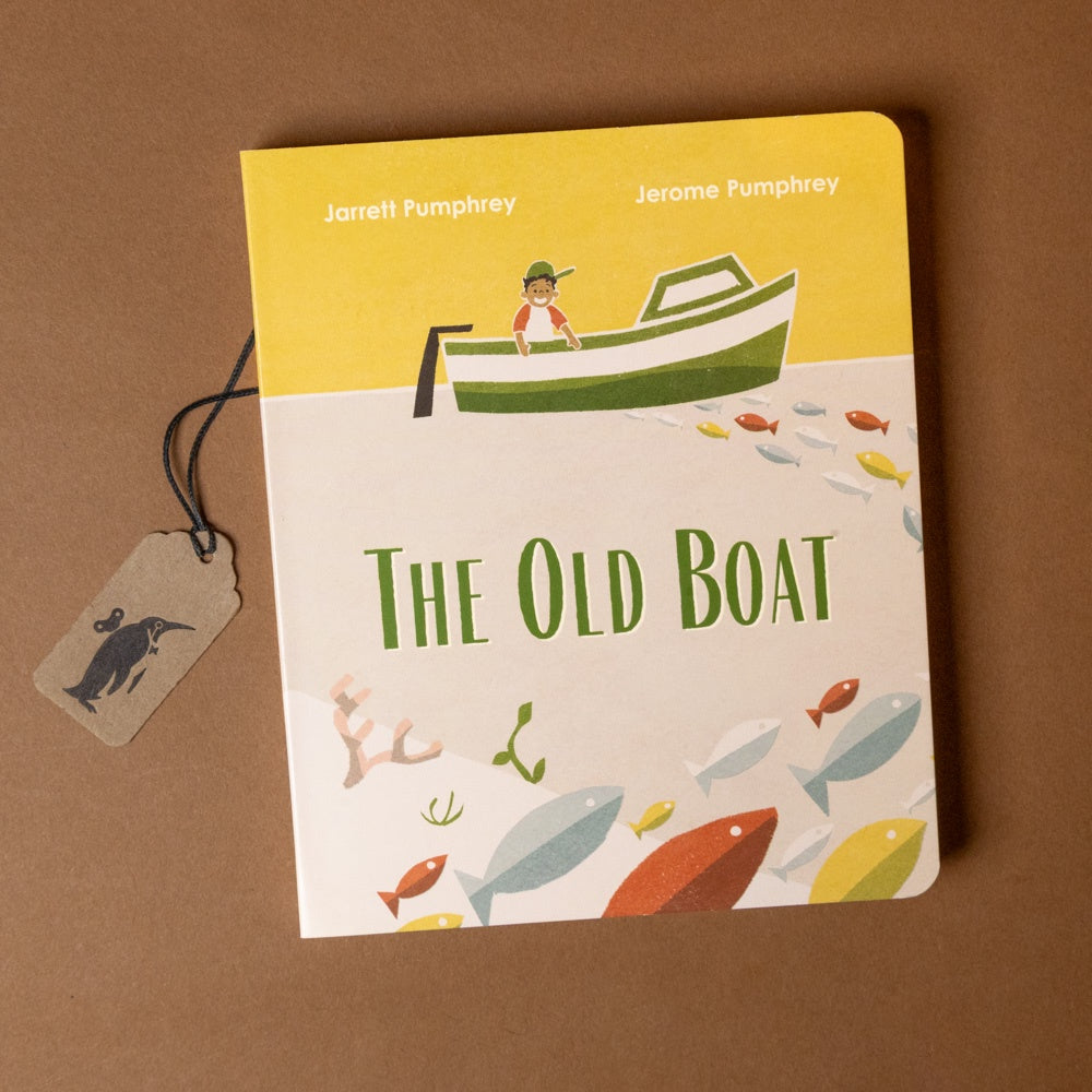Book titled 'The Old Boat' with a yellow cover and illustration of a boy in a boat on a brown background.
