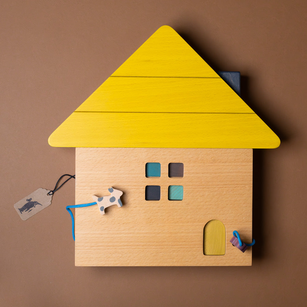 Wooden house puzzle with a yellow roof on a brown background