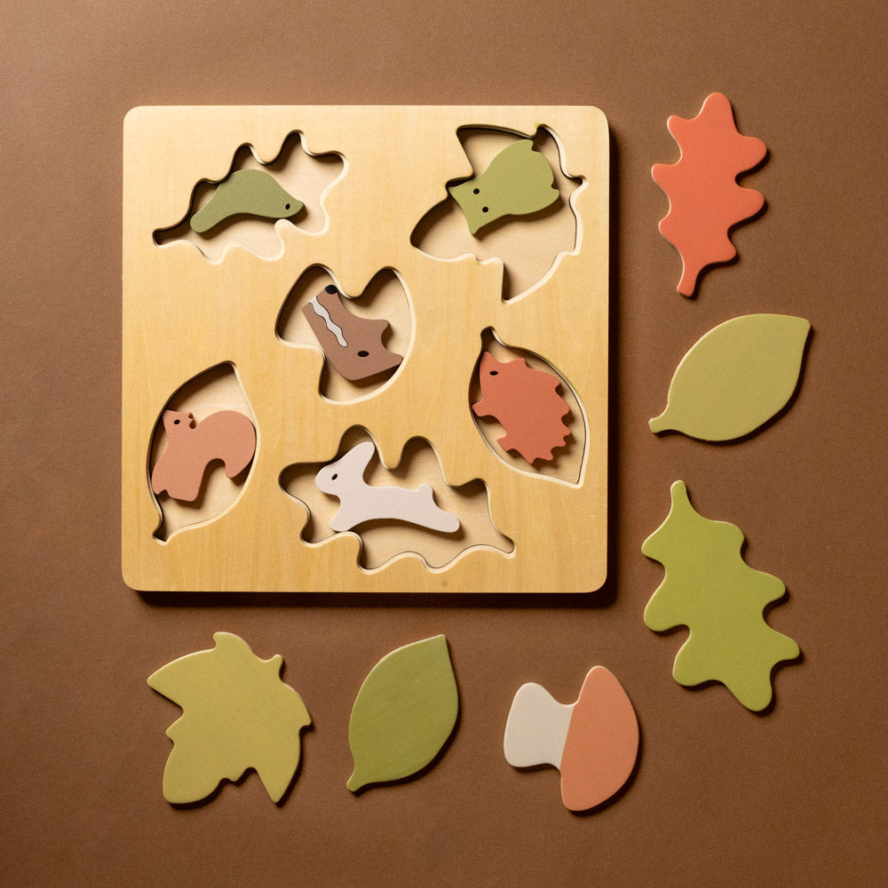 wooden-forest-puzzle Wooden puzzle with animal and leaf shapes on a brown background