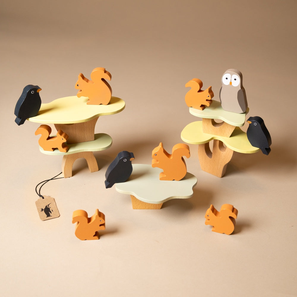 wooden-stacking-squirrels-game Wooden animal toys including squirrels, an owl, and a bird on a beige background